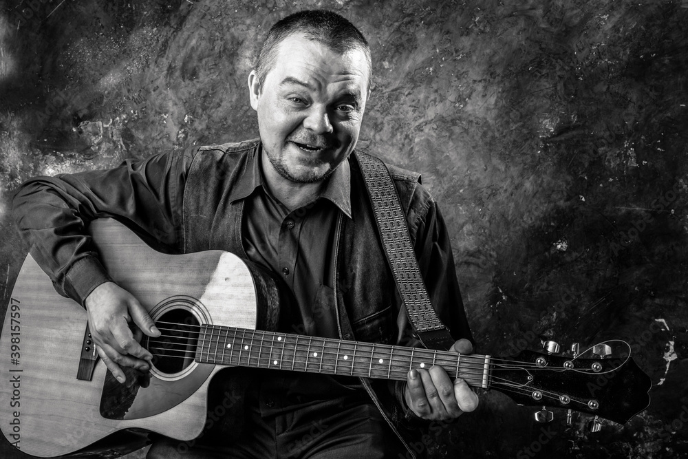 Obraz premium Mature musician plays acoustic guitar emotional studio portrait.