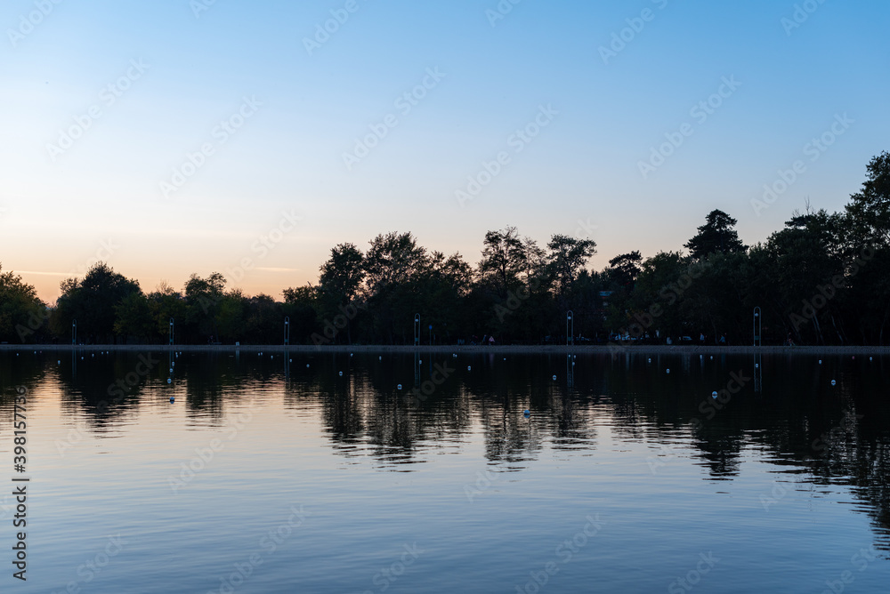 Sunset vibrant reflections in deep blue water symmetry silhouette landscape nature alley park shore forest island