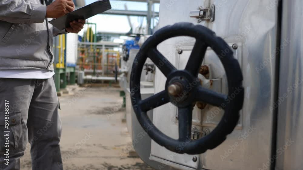 A factory technician is inspecting the plant liquid supply control device. Petroleum oil and gas refinery plant A factory technician is inspecting the plant liquid supply control device. Petroleum oil and gas refinery plant