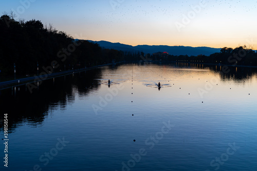 Kayaks racing in canal water reservoir for rowing sport practice on sunset vibrant background in Plovdiv, Bulgaria