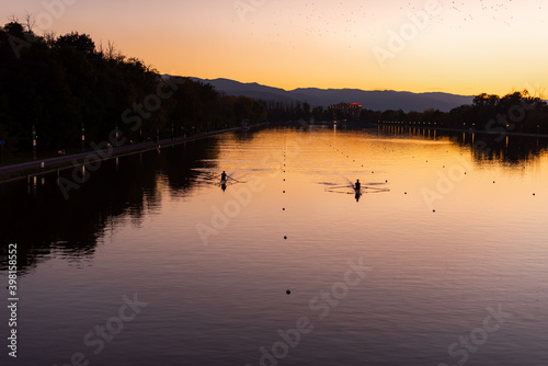 Kayaks racing in canal water reservoir for rowing sport practice on sunset vibrant background in Plovdiv, Bulgaria