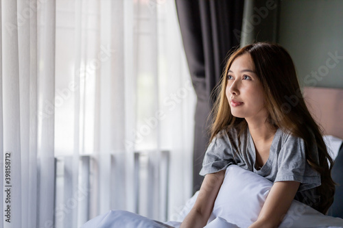 Beautiful long hair women sitting on the bed. while looking up for something.