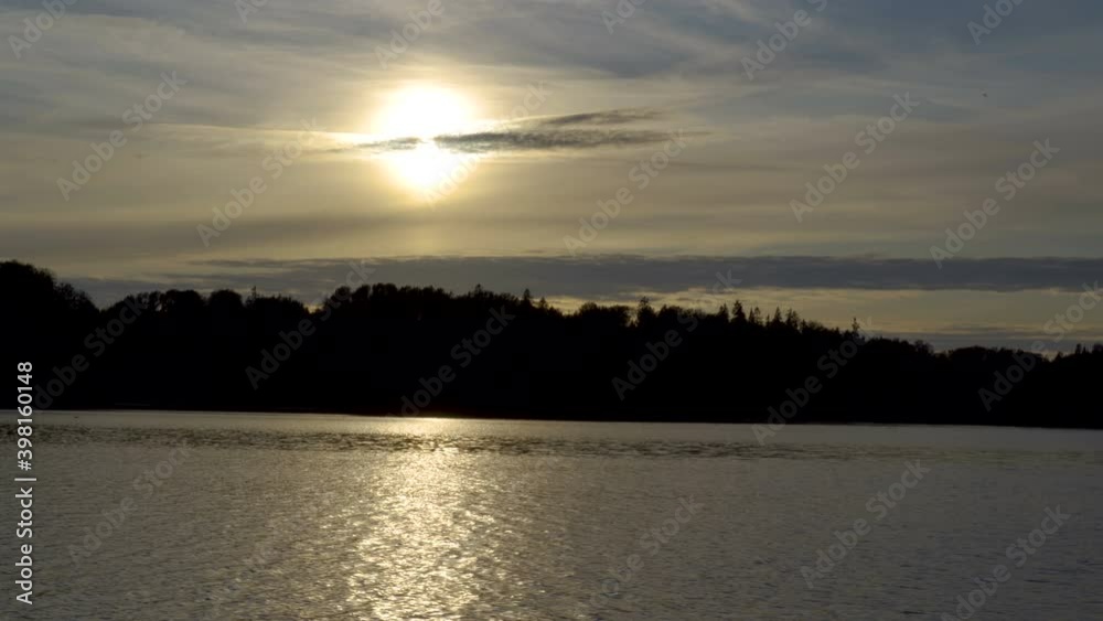 The sun setting from the sky while cruising in the ocean on a late afternoon view in Estonia The sun setting from the sky while cruising in the ocean on a late afternoon view in Estonia