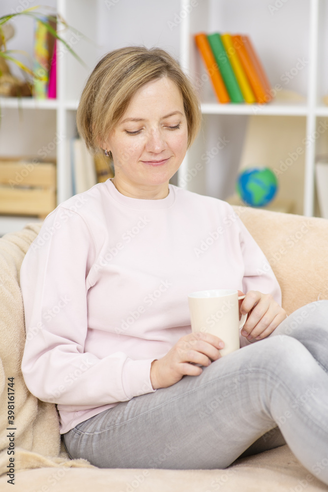 Young woman sitting at home on sofa with mug Young woman sitting at home on sofa with mug