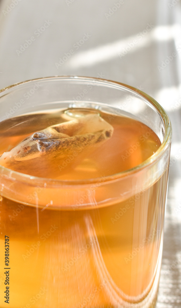 A beautiful glass filled with golden tea in the afternoon sunlight. A beautiful glass filled with golden tea in the afternoon sunlight.