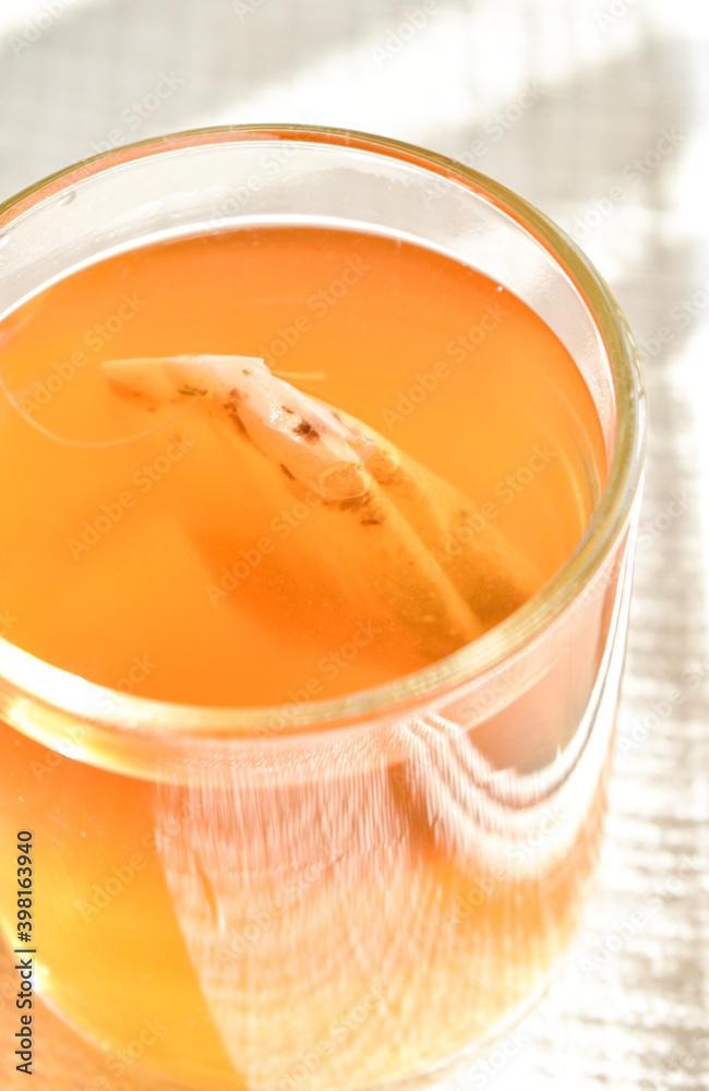A beautiful glass filled with golden tea in the afternoon sunlight. A beautiful glass filled with golden tea in the afternoon sunlight.