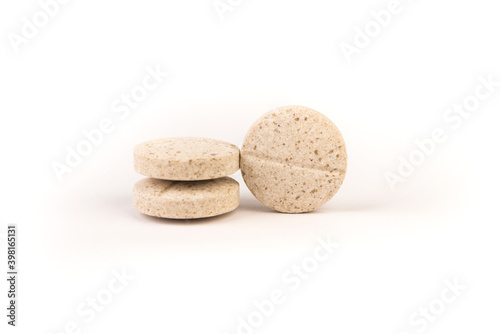 Three yellow and brown flecked chewable dog multivitamin isolated over white