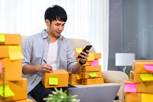 man entrepreneur using smartphone and prepare parcel boxes for deliver to customer at home office, (SME business)