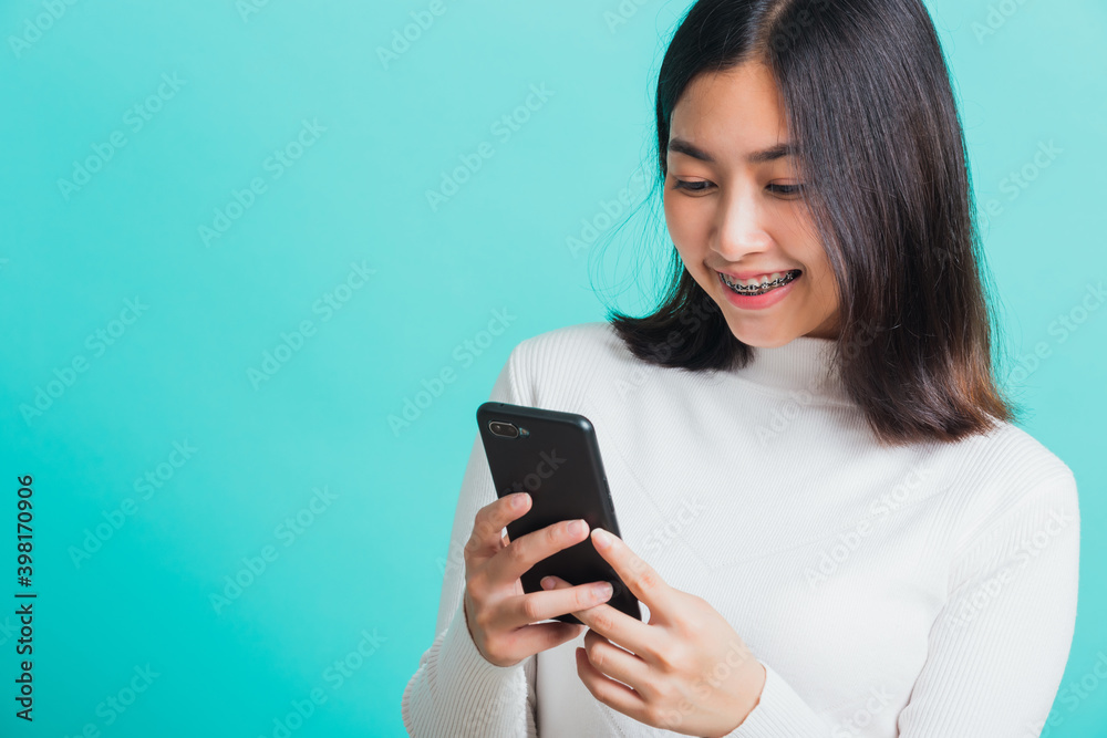 Portrait of Asian woman smile she holding and typing text message on a smartphone, female excited cheerful her reading mobile phone some social media isolated on a blue background, Technology concept Portrait of Asian woman smile she holding and typing text message on a smartphone, female excited cheerful her reading mobile phone some social media isolated on a blue background, Technology concept