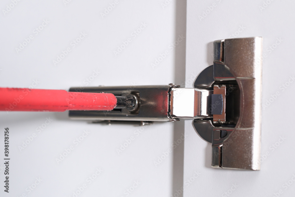 Man adjusts hinges soft closing on the cabinet door. Man adjusts hinges soft closing on the cabinet door.