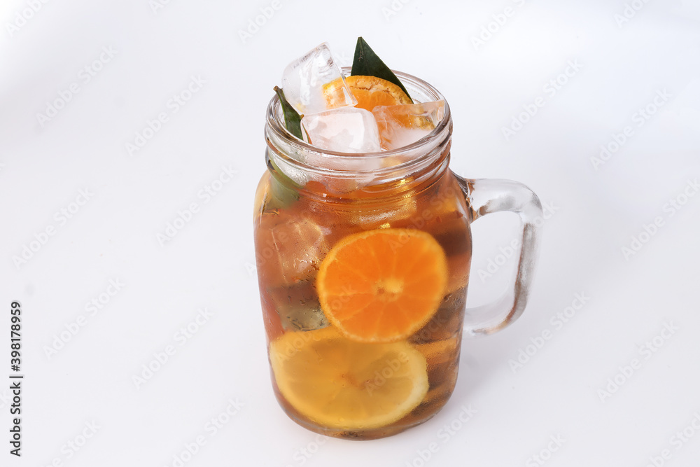 Liquid ice lemon orange tea with slice green leaf cinnamon stick in transparent glass jar mug on white background Liquid ice lemon orange tea with slice green leaf cinnamon stick in transparent glass jar mug on white background
