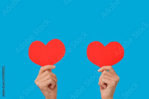 Female blogger hold in hands little red hearts, dancing to music rhythm isolated on blue background. Like blogging blog social network tenderness concept. Valentines day international women
