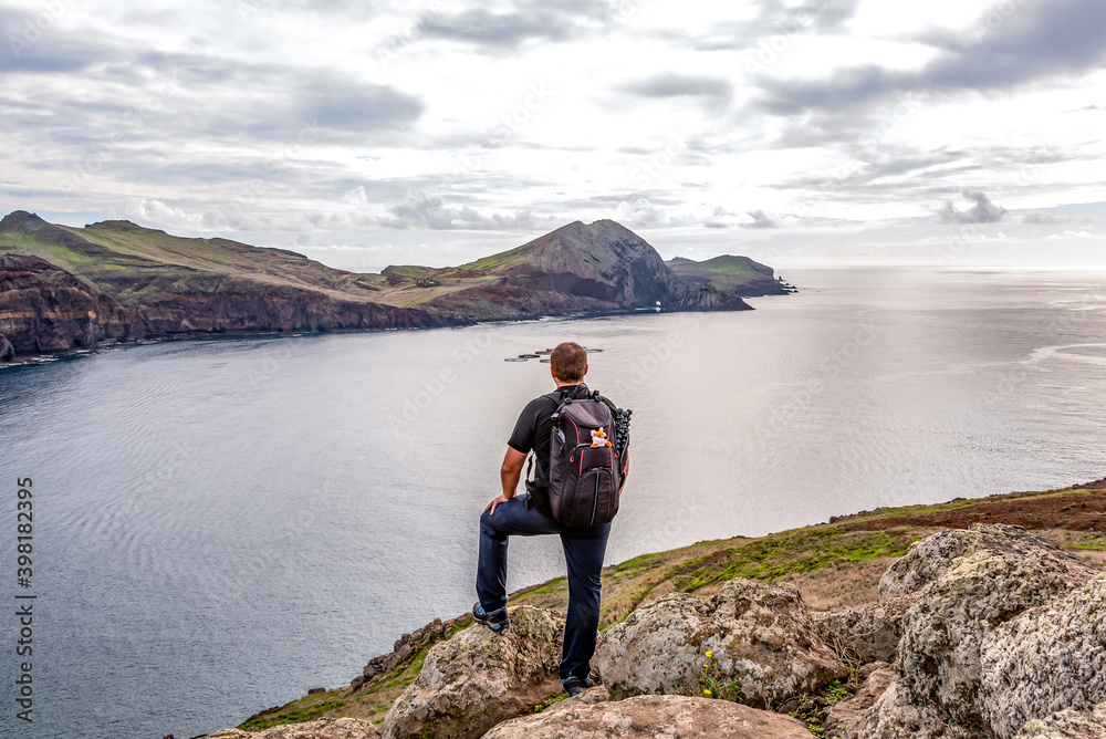 Man hiking rocky cliffs clear near water of Atlantic Ocean bay Ponta de Sao Lourenco, the island of Madeira, Portugal