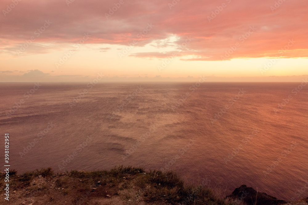 Seascape at red sunset. On the edge of a cliff. Summer-autumn. Horizontal photo. A soft picture. The view from the top