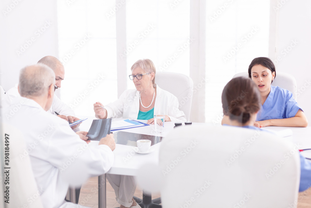 Team of expert doctors sitting at desk in conference room having a briefing. Clinic expert therapist talking with colleagues about disease, medicine professional