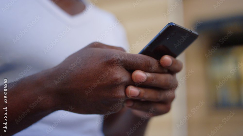 Unknown afro guy texting message on street. African man hands with mobile phone Unknown afro guy texting message on street. African man hands with mobile phone