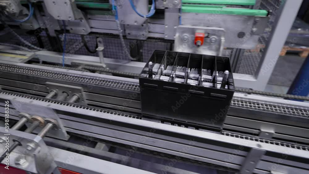 Automatic line for the assembly of car batteries. The black batteries move and collect on the conveyor belt.