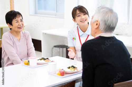 食事中の高齢の入居者たちと介護施設の女性職員 photo