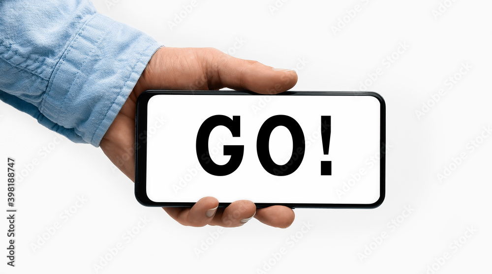 Closeup of a male hand holding Smartphone with word GO on display Closeup of a male hand holding Smartphone with word GO on display