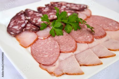 Cold cuts with parsley on a white plate. Close-up, selective focus