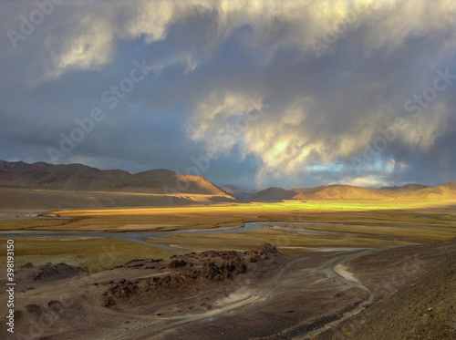 Spectacular light before sunset on mountain surrounded plain with river along the high-altitude Pamir Highway near Murghab town in Gorno-Badakshan  Tajikistan