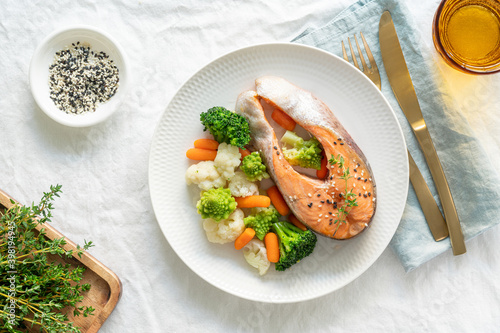 Steam salmon and vegetables, top view. Paleo, keto, fodmap, dash diet. Mediterranean diet with steamed fish. Healthy concept, white plate on gray table, gluten free, lectine free photo