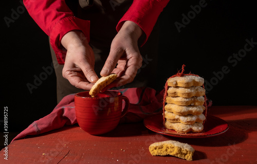 hand holding red biscuit gift black background cup coffee tea photo