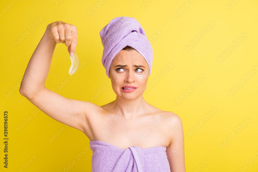 Portrait of pretty disappointed girl holding in hand applying patches worrying isolated over bright yellow color background Portrait of pretty disappointed girl holding in hand applying patches worrying isolated over bright yellow color background