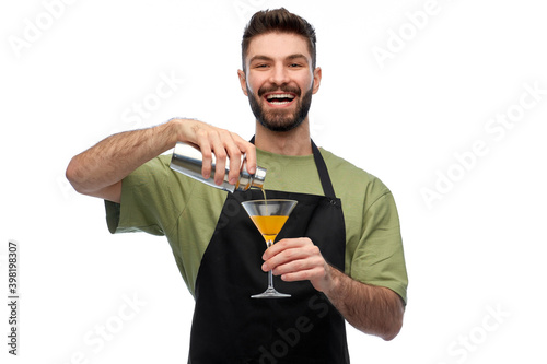 alcohol drinks, people and job concept - happy smiling barman in black apron with shaker and glass preparing martini cocktail over white background photo