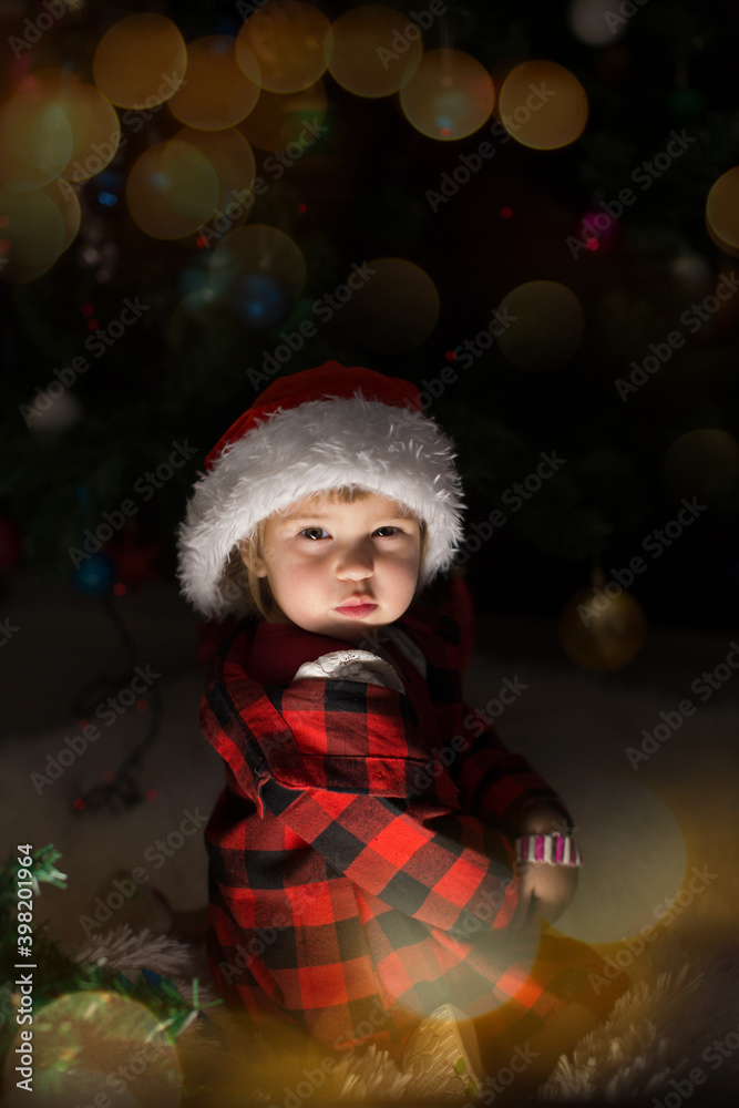 a child in red clothes is sitting waiting for the new year. the concept of celebrating Christmas at midnight. holiday costume a child in red clothes is sitting waiting for the new year. the concept of celebrating Christmas at midnight. holiday costume