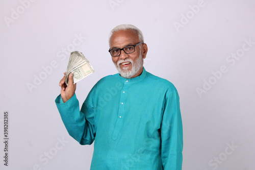 Portrait of happy Indian asian senior man holding indian currency notes of five hundred.