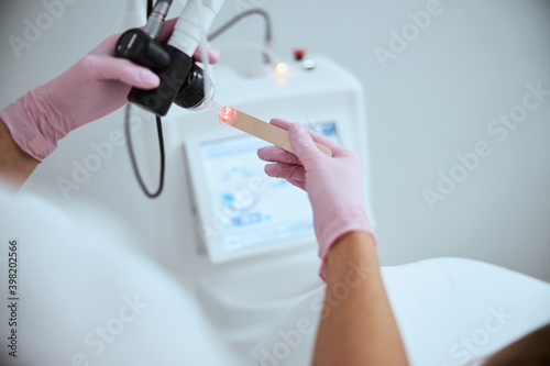 Doctor in latex gloves testing a beauty device