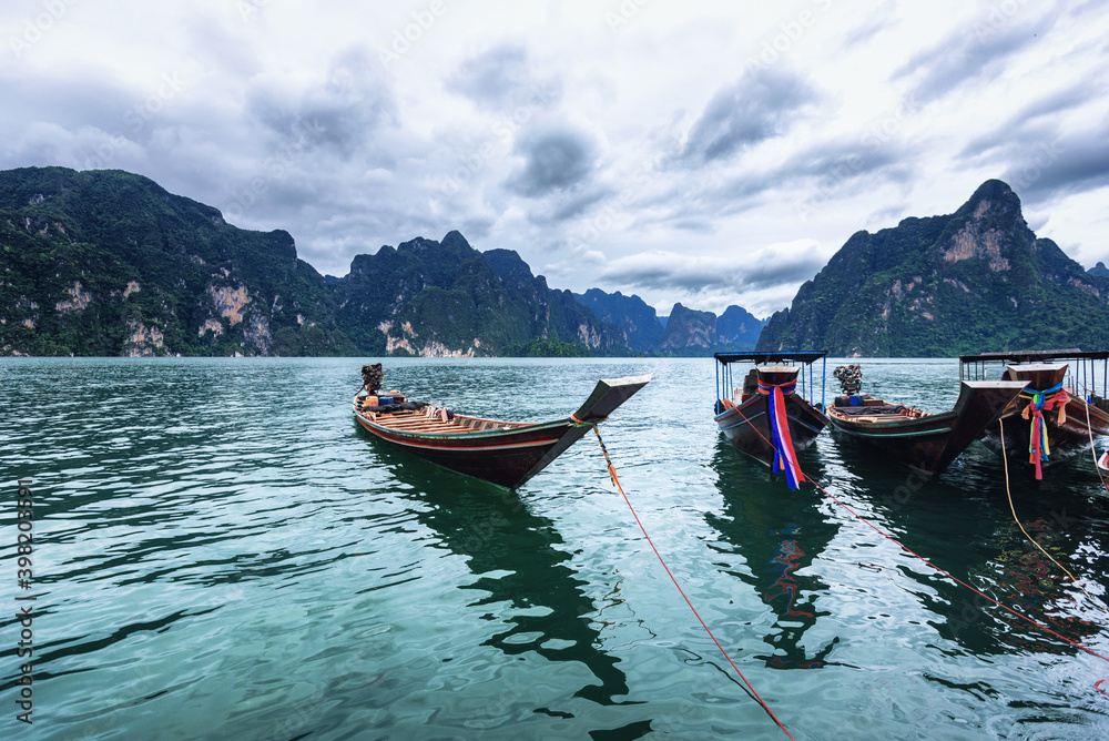 Long-tailed boat group floating on the asia lake in the among the islands with mountains in background at Surat Thani Province of Thailand.