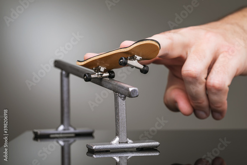 A man plays with a fingerboard on a gray metal railing