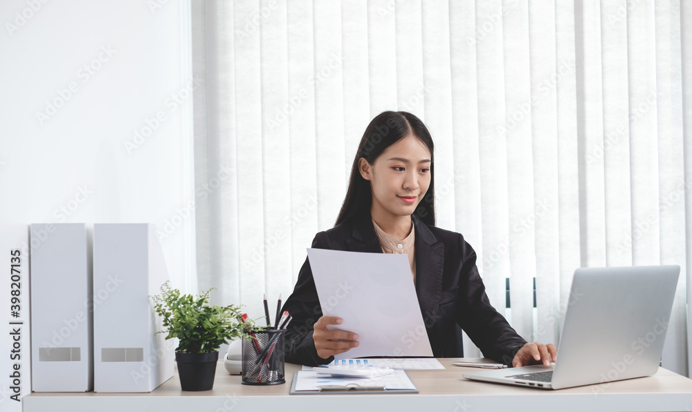 Asian businesswomen sit at their desks and calculate financial graphs showing results about their investments, plan a successful business growth process in the office Asian businesswomen sit at their desks and calculate financial graphs showing results about their investments, plan a successful business growth process in the office