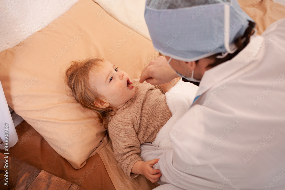 The doctor checks the throat of a little girl at home. Sick baby, home quarantine, coronavirus The doctor checks the throat of a little girl at home. Sick baby, home quarantine, coronavirus