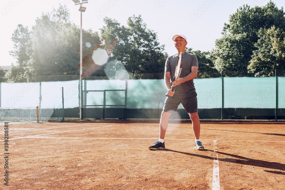 Middle-aged man playing tennis on outdoor tennis filed
