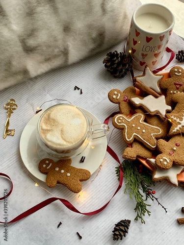 Hot winter drink: chocolate with whipped cream in glass mug. Christmas time. Cozy home atmosphere, white background. Homemade gingerbread cookies, christmas lights. Banner, copy space for text