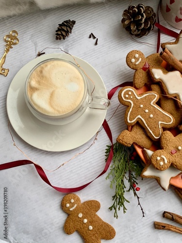 Winter cappuccino coffee in a white cup with man christmas gingerbread cookies. Christmas mood. New Year atmosphere. Cozy home.