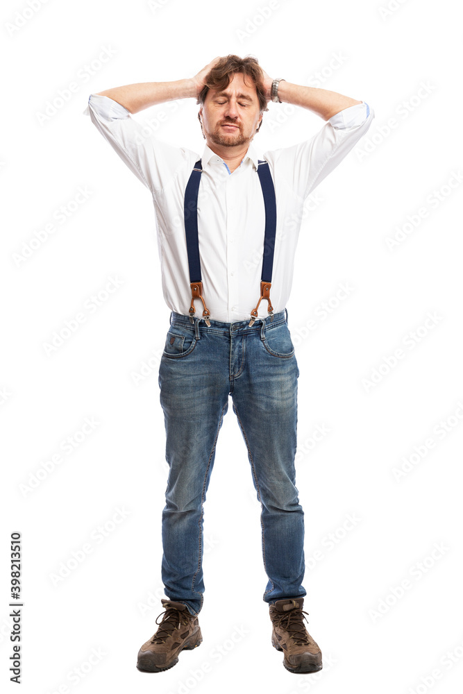 A man with red hair in a white shirt and jeans with suspenders is standing with his hands up to his head. Full height. Isolated on a white background. Vertical. A man with red hair in a white shirt and jeans with suspenders is standing with his hands up to his head. Full height. Isolated on a white background. Vertical.