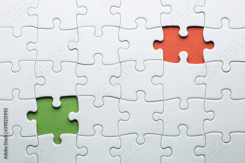 puzzle is missing two pieces to be completed in different colors. white pieces and one piece in green and one in orange to add text