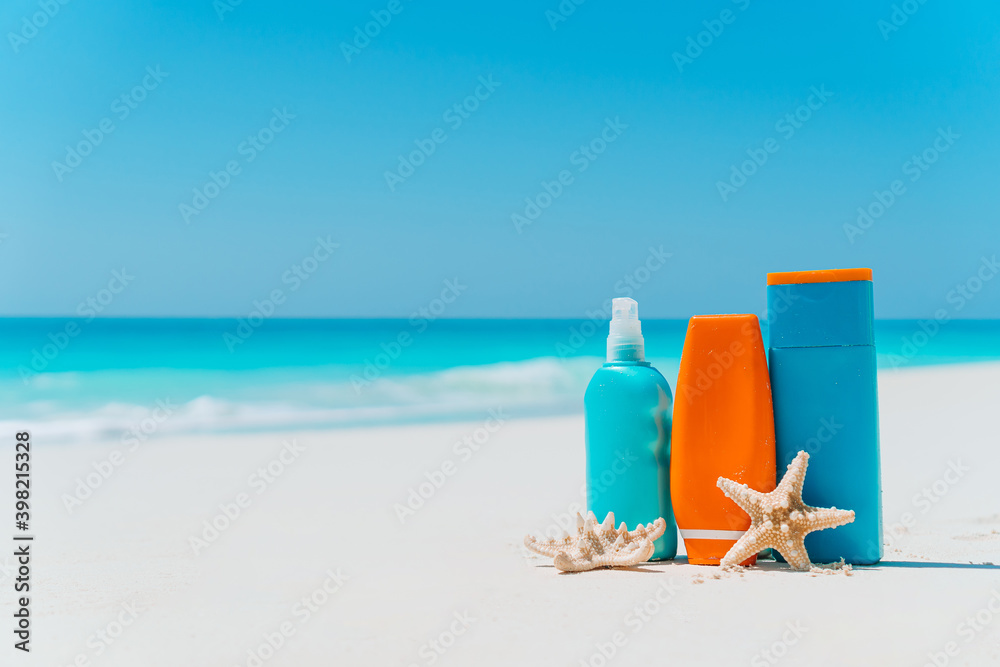 Suncream bottles, sunglasses, starfish on white sandy beach Suncream bottles, sunglasses, starfish on white sandy beach