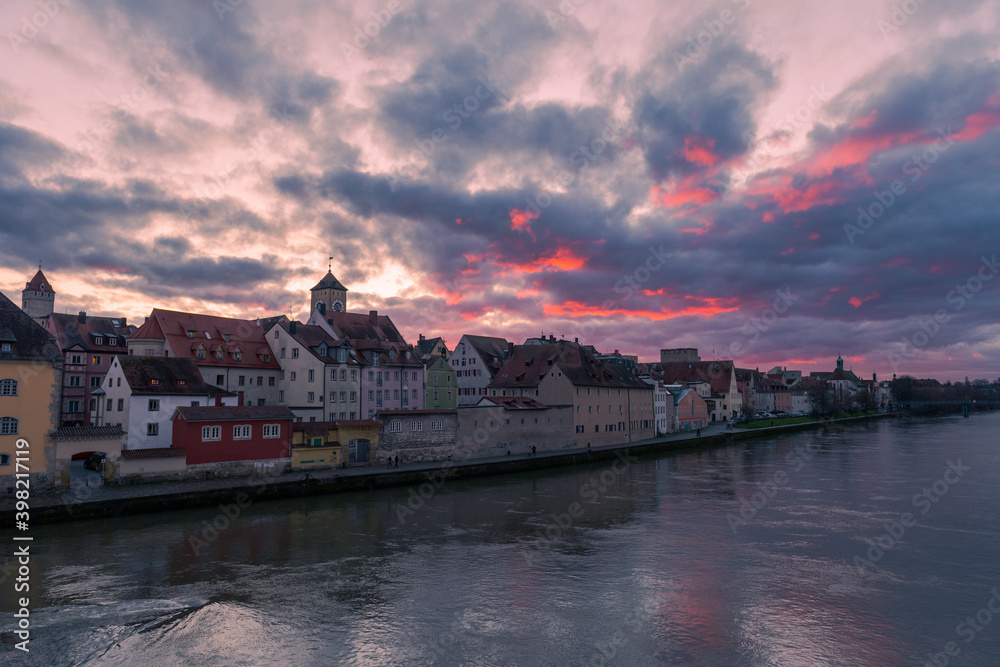 Panoramic view of the famous skyline of Regensburg in Bavaria seen from the Stone Bridge with dramatic clouds in evening sky