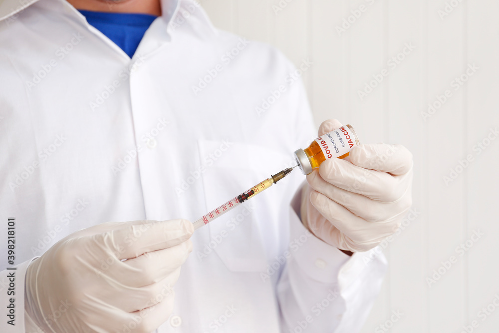 Macro shot of doctor's hands in latex gloves filling the syringe with new covid-19 vaccine from the vial. Close up, copy space, background. Macro shot of doctor's hands in latex gloves filling the syringe with new covid-19 vaccine from the vial. Close up, copy space, background.