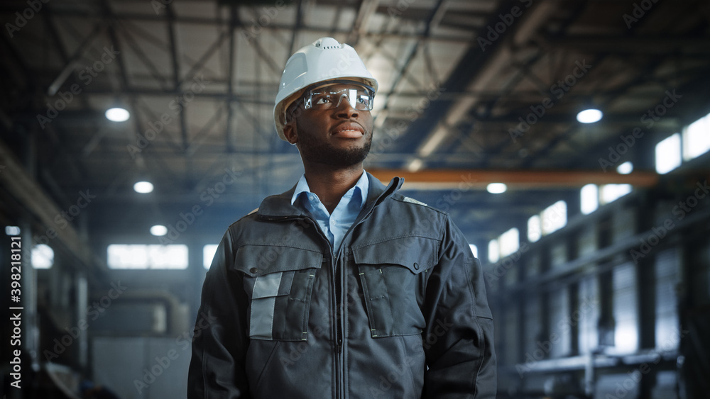 Portrait of Professional Heavy Industry Engineer/Worker Wearing Uniform, Glasses, Hard Hat in Steel Factory. Smiling African American Industrial Specialist Standing in Metal Construction Manufacture. Portrait of Professional Heavy Industry Engineer/Worker Wearing Uniform, Glasses, Hard Hat in Steel Factory. Smiling African American Industrial Specialist Standing in Metal Construction Manufacture.
