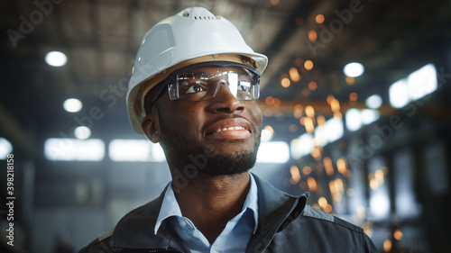 Foto Happy Professional Heavy Industry Engineer/Worker Wearing Uniform, Glasses and Hard Hat in a Steel Factory