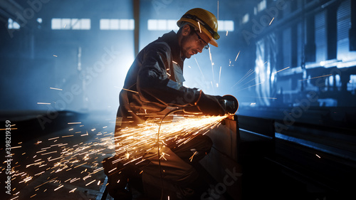 Photographie Heavy Industry Engineering Factory Interior with Industrial Worker Using Angle Grinder and Cutting a Metal Tube