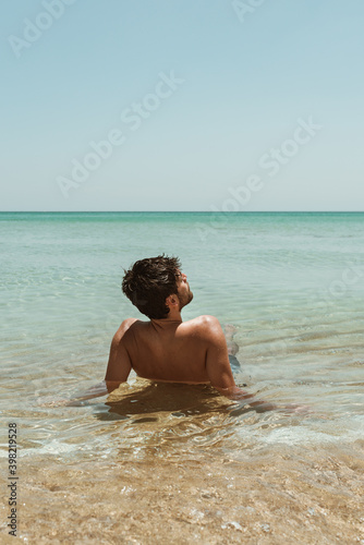 Young male on holidays enjoy floating on a crystal clear water beach of Australia.