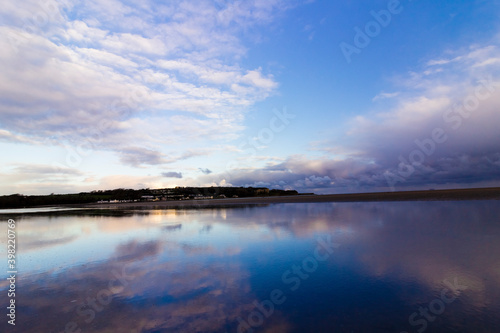 Beautiful twilight reflection cloudscape and skyscape on the water pooled surface of Red Wharf Bay, Isle of Anglesey, North Wales