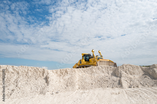 Yellow bulldozer moving limestone in the quarry. Faxe Kalkbrud, Denmark.